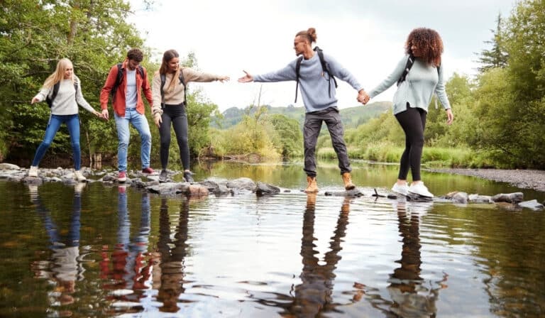 group of people helping each other cross a river