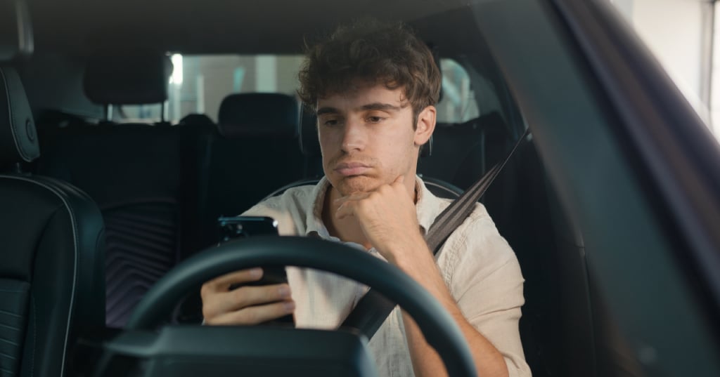 man sitting in his car comparing outpatient treatment costs against DUI court fees and lost wages on his phone