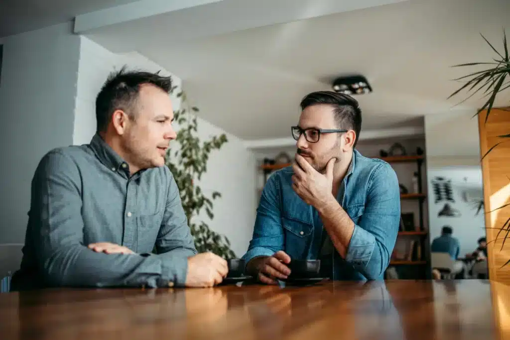 Two people talking over coffee, illustrating how finding the right recovery sponsor works in 12-step programs