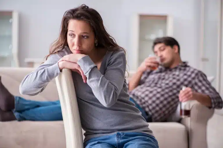 Partner sitting in chair after setting healthy boundaries with a loved one facing addiction lying on couch